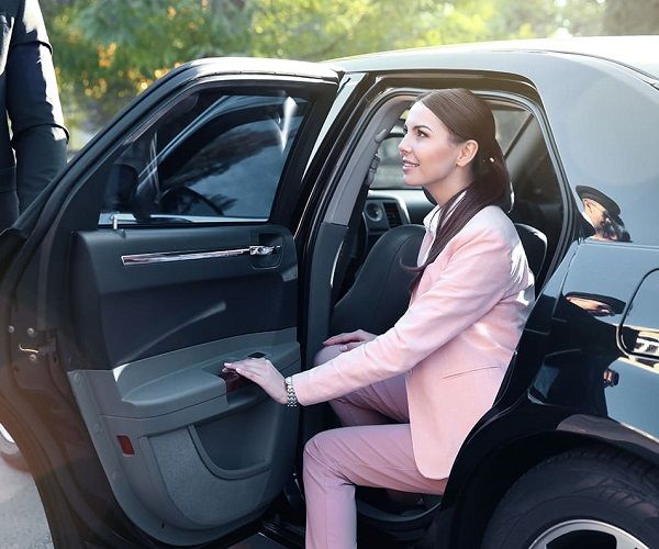 Traslado a aeropuerto, clienta saliendo de un coche de alta gama, con el chofer al lado